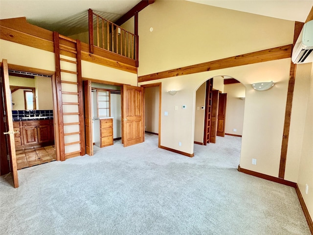 444 Windwalker Trl, Stevensville, MT 59870 - unfurnished living room featuring light carpet, high vaulted ceiling, arched walkways, a wall mounted AC, and baseboards