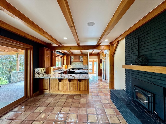 444 Windwalker Trl, Stevensville, MT 59870 - kitchen featuring beam ceiling, a peninsula, a brick fireplace, brown cabinetry, and recessed lighting