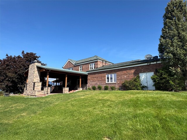 444 Windwalker Trl, Stevensville, MT 59870 - back of property featuring a lawn, a chimney, and brick siding