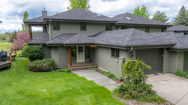 259 Eagle Bend Dr, Bigfork, MT 59911 - prairie-style home featuring an attached garage, a chimney, concrete driveway, a front yard, and a shingled roof
