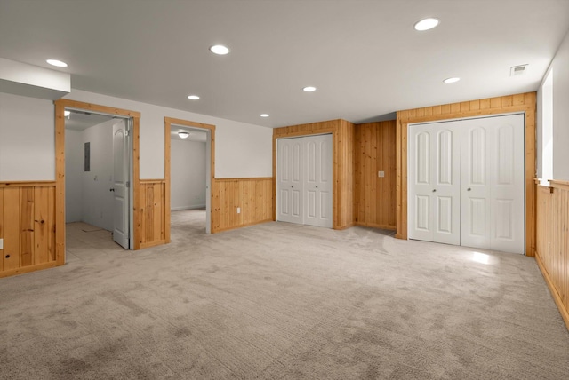 515 W Oregon St, Kalispell, MT 59901 - unfurnished bedroom with wooden walls, wainscoting, recessed lighting, light carpet, and two closets