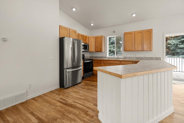 515 W Oregon St, Kalispell, MT 59901 - kitchen featuring appliances with stainless steel finishes, a peninsula, a sink, light wood-style floors, and plenty of natural light