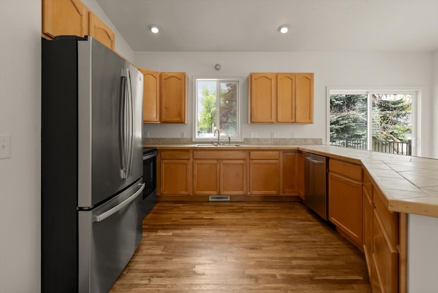 515 W Oregon St, Kalispell, MT 59901 - kitchen featuring stainless steel appliances, tile countertops, light wood-type flooring, a sink, and a peninsula