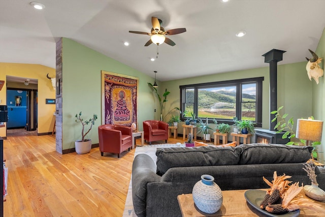 51943 Kuntz Ln, Charlo, MT 59824 - living room featuring vaulted ceiling, ceiling fan, a wood stove, light wood-type flooring, and baseboards