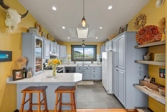 51943 Kuntz Ln, Charlo, MT 59824 - kitchen with freestanding refrigerator, a peninsula, under cabinet range hood, a sink, and backsplash