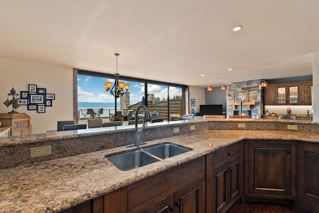 5675 US Highway 93 S Unit 10, Somers, MT 59932 - kitchen with a sink, light stone counters, pendant lighting, dark brown cabinets, and a chandelier