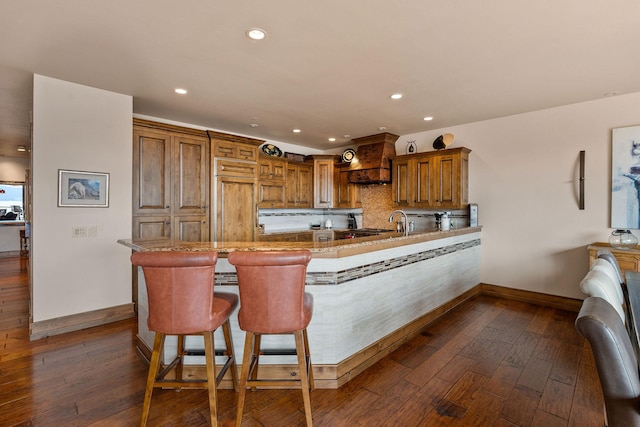 5675 US Highway 93 S Unit 10, Somers, MT 59932 - kitchen featuring baseboards, dark wood-style flooring, brown cabinetry, a peninsula, and decorative backsplash