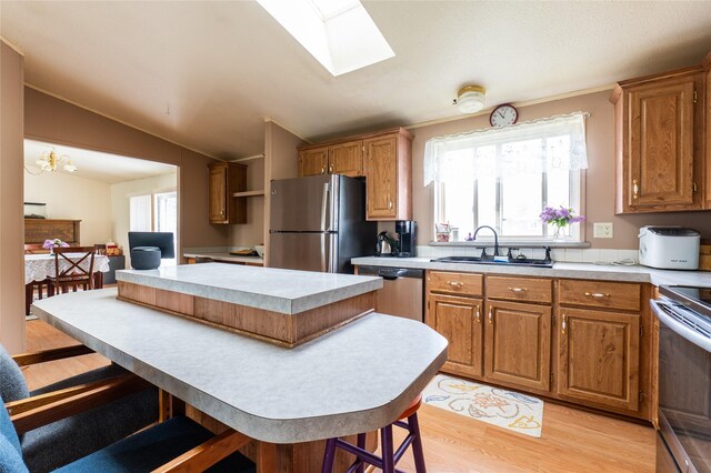 1709 20th Ave S, Great Falls, MT 59405 - kitchen featuring appliances with stainless steel finishes, a sink, a kitchen island, light wood-type flooring, and vaulted ceiling