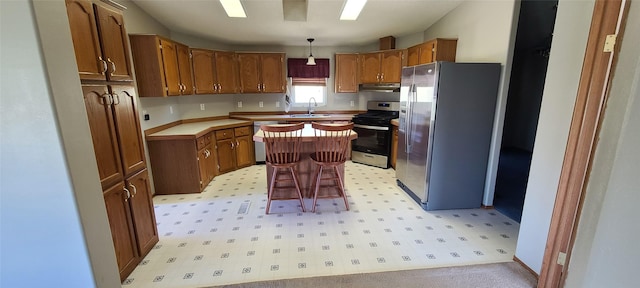 8 Teresa Ln, Great Falls, MT 59404 - kitchen featuring stainless steel appliances, under cabinet range hood, a center island, brown cabinets, and light countertops