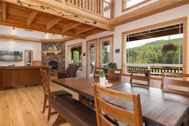 12520 Pinkham Creek Rd, Rexford, MT 59930 - dining space featuring track lighting, light wood-style floors, healthy amount of natural light, a stone fireplace, and wooden ceiling with exposed beams