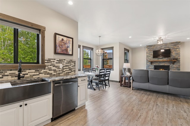 1066 Mill Creek Drive Mill Creek Drive, Bigfork, MT 59911 - kitchen featuring dishwasher, a sink, a stone fireplace, light wood finished floors, and tasteful backsplash