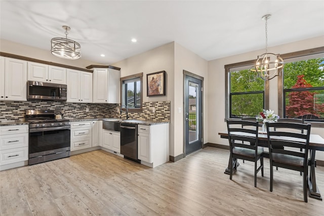 1066 Mill Creek Drive Mill Creek Drive, Bigfork, MT 59911 - kitchen with stainless steel appliances, a chandelier, a sink, backsplash, and plenty of natural light