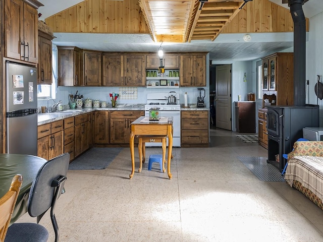 89 Wild Rose Trl, Roberts, MT 59070 - kitchen featuring gas range gas stove, freestanding refrigerator, a wood stove, a sink, and dark aggregate flooring