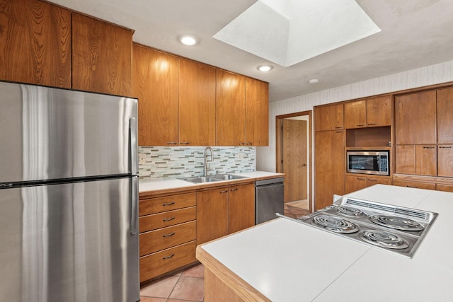 160 Sherwood Ln, Kalispell, MT 59901 - kitchen with appliances with stainless steel finishes, a sink, a skylight, light countertops, and tasteful backsplash
