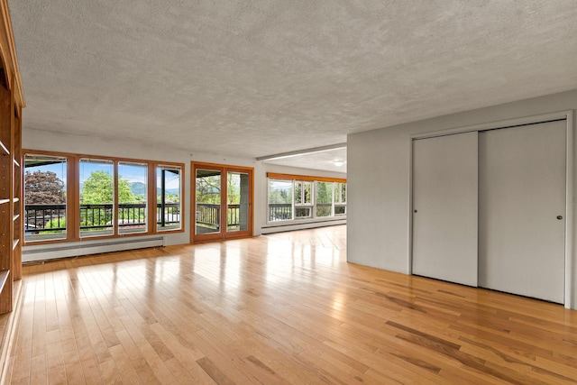 160 Sherwood Ln, Kalispell, MT 59901 - unfurnished living room featuring a baseboard radiator, a textured ceiling, and light wood-style flooring