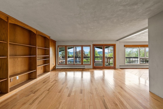 160 Sherwood Ln, Kalispell, MT 59901 - unfurnished living room with a baseboard heating unit, built in shelves, light wood-type flooring, and a textured ceiling
