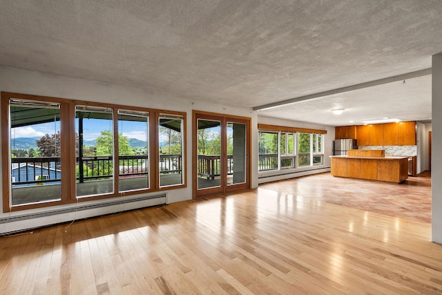 160 Sherwood Ln, Kalispell, MT 59901 - unfurnished living room with baseboard heating, light wood-style flooring, and a textured ceiling