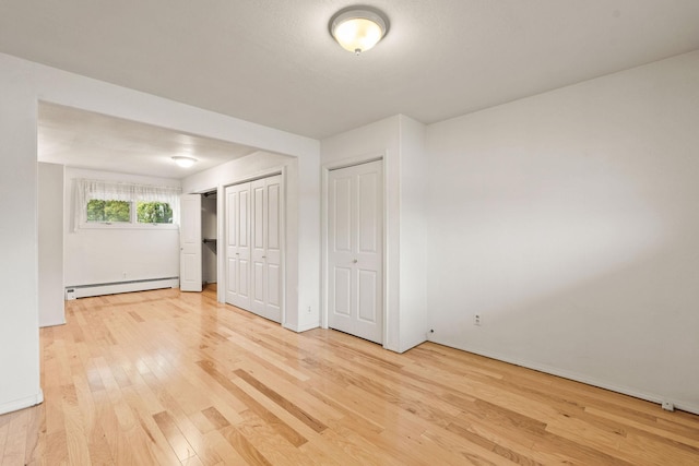 160 Sherwood Ln, Kalispell, MT 59901 - unfurnished bedroom with a baseboard radiator, light wood-style flooring, multiple closets, and baseboards