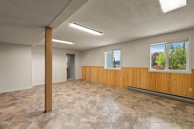 160 Sherwood Ln, Kalispell, MT 59901 - empty room featuring a wainscoted wall, wooden walls, plenty of natural light, a baseboard heating unit, and stone finish flooring