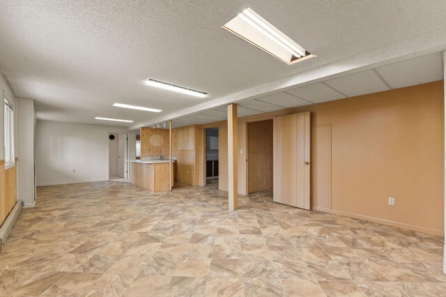 160 Sherwood Ln, Kalispell, MT 59901 - finished basement with baseboards, a textured ceiling, stone finish flooring, a baseboard radiator, and bar