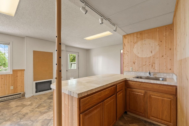 160 Sherwood Ln, Kalispell, MT 59901 - kitchen featuring wood walls, light countertops, rail lighting, brown cabinets, and a peninsula