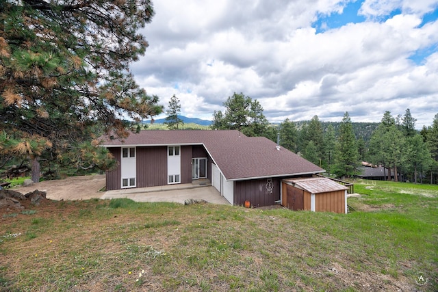 15 Vigilante Trl, Clancy, MT 59634 - rear view of house with a patio, a yard, a shingled roof, and an attached garage