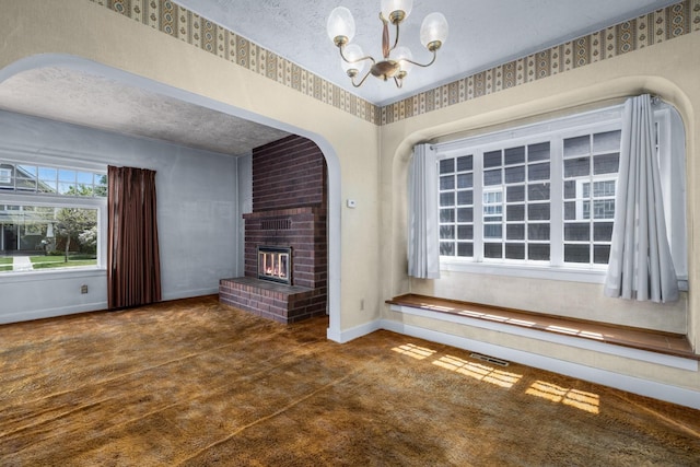 414 Somers Ave, Whitefish, MT 59937 - unfurnished living room featuring a chandelier, carpet, baseboards, a brick fireplace, and a textured ceiling