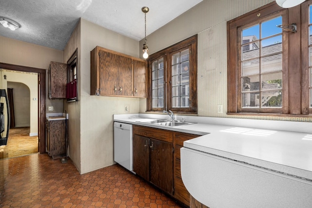414 Somers Ave, Whitefish, MT 59937 - kitchen featuring dishwasher, a sink, light countertops, wallpapered walls, and hanging light fixtures