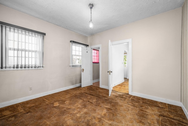 414 Somers Ave, Whitefish, MT 59937 - unfurnished bedroom with baseboards, carpet floors, a textured ceiling, and arched walkways