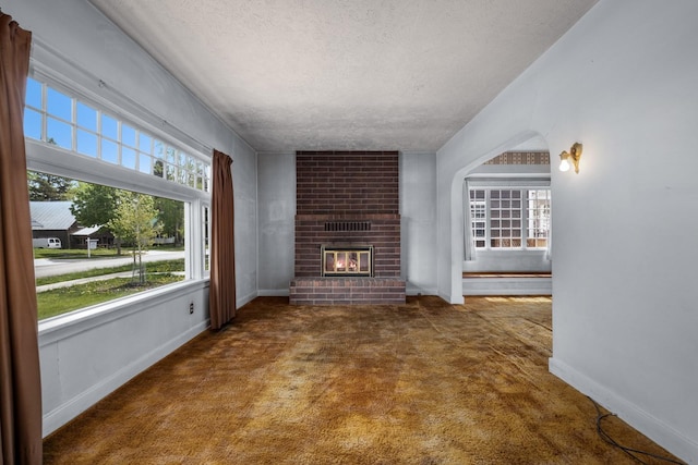 414 Somers Ave, Whitefish, MT 59937 - unfurnished living room with carpet flooring, a textured ceiling, a fireplace, and baseboards