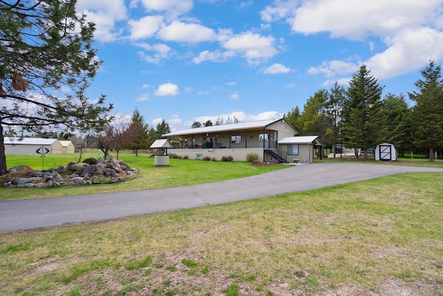 245 Blanchard Lake Rd, Whitefish, MT 59937 - view of front facade featuring a storage unit, a front lawn, stairway, covered porch, and driveway