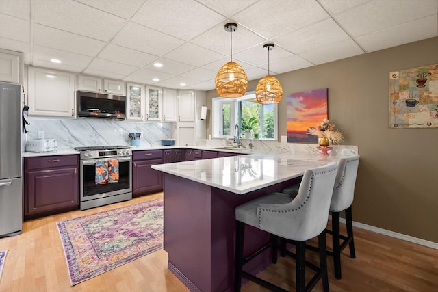 245 Blanchard Lake Rd, Whitefish, MT 59937 - kitchen featuring stainless steel appliances, a peninsula, light wood-style flooring, a breakfast bar, and white cabinetry