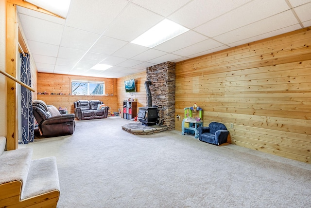 30 Knapp Ln, Kalispell, MT 59901 - living room featuring a wood stove, wooden walls, carpet, and a drop ceiling