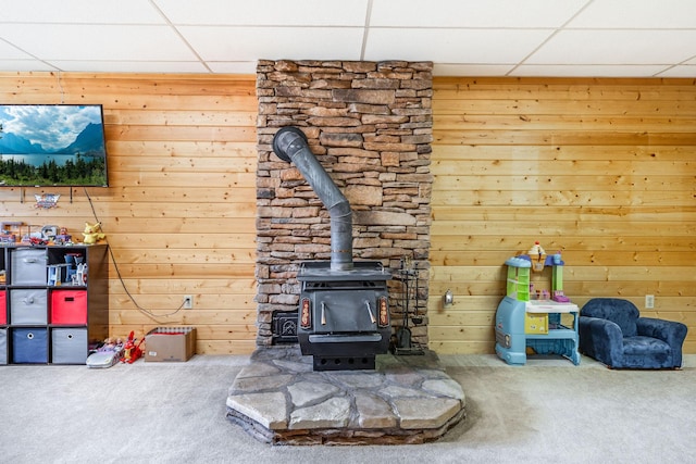 30 Knapp Ln, Kalispell, MT 59901 - unfurnished living room featuring carpet, a drop ceiling, a wood stove, and wooden walls