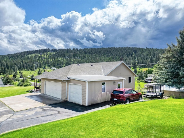 30 Knapp Ln, Kalispell, MT 59901 - view of side of home featuring a view of trees, a shingled roof, a lawn, and a garage