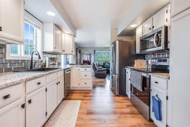 30 Knapp Ln, Kalispell, MT 59901 - kitchen featuring stainless steel appliances, a sink, white cabinets, decorative backsplash, and light wood-type flooring