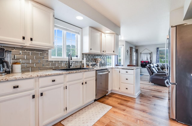 30 Knapp Ln, Kalispell, MT 59901 - kitchen with stainless steel appliances, a sink, light wood-style floors, open floor plan, and a peninsula