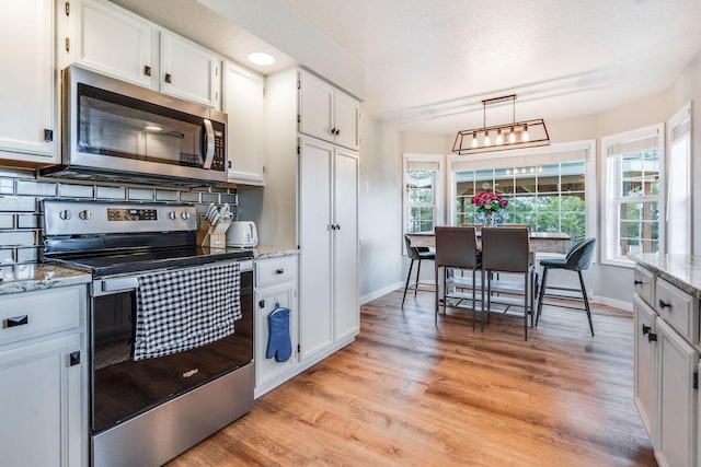 30 Knapp Ln, Kalispell, MT 59901 - kitchen with appliances with stainless steel finishes, light wood finished floors, baseboards, white cabinets, and light stone counters