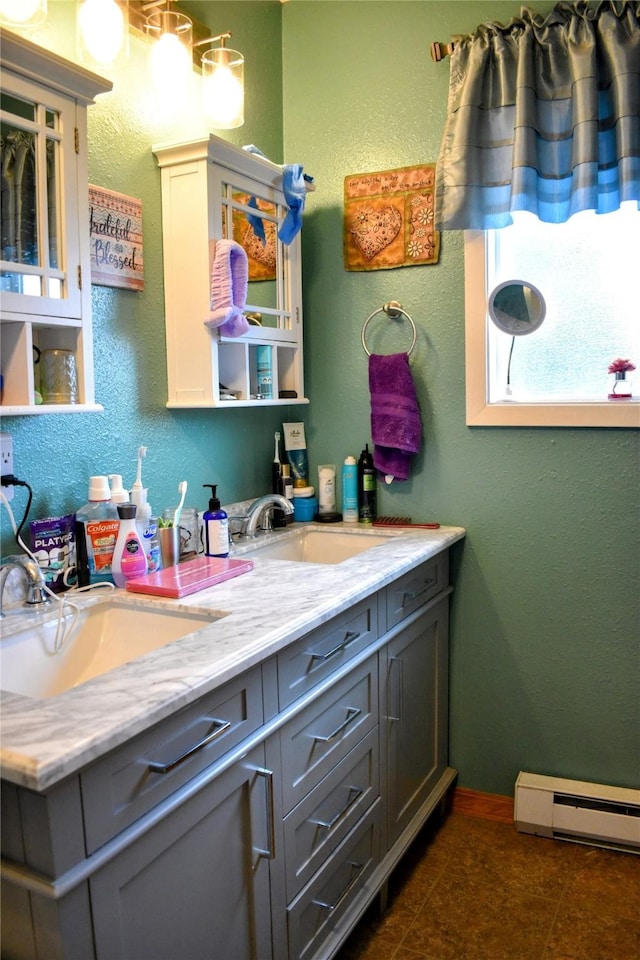 83 Indian Head Rd, Libby, MT 59923 - bathroom with double vanity, baseboard heating, a textured wall, baseboards, and tile patterned floors