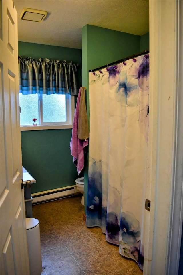 83 Indian Head Rd, Libby, MT 59923 - bathroom with baseboard heating, toilet, and a shower with curtain