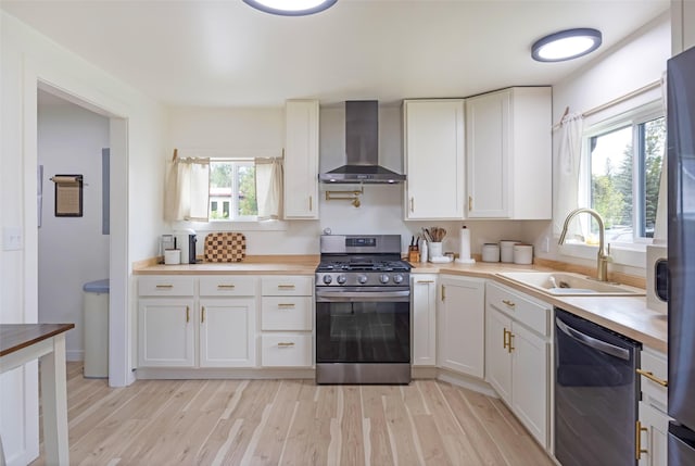 215 Tower St, Missoula, MT 59804 - kitchen with appliances with stainless steel finishes, wall chimney range hood, a sink, light wood finished floors, and healthy amount of natural light