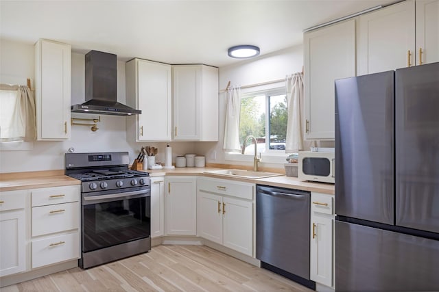 215 Tower St, Missoula, MT 59804 - kitchen featuring stainless steel appliances, wall chimney range hood, a sink, light countertops, and white cabinetry