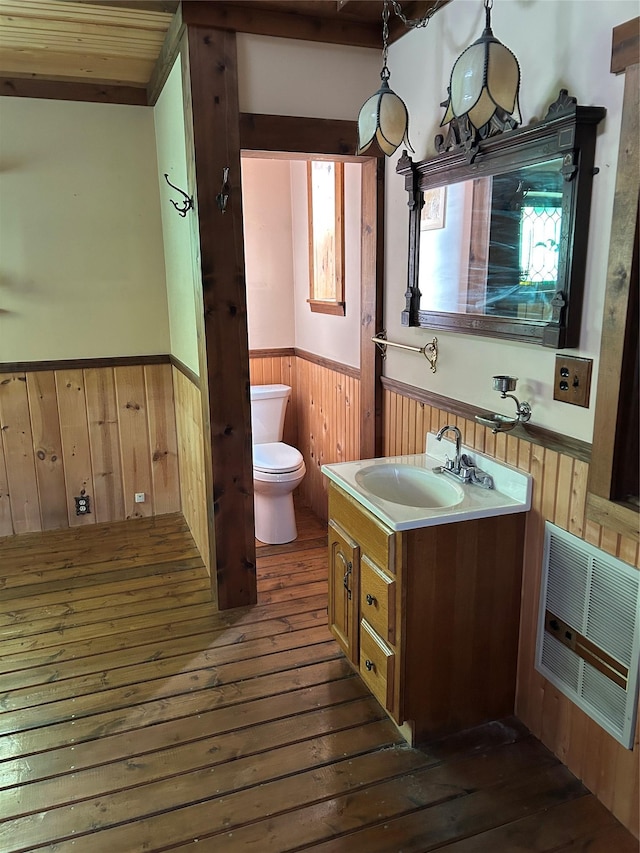 33562 Fox Rd, Polson, MT 59860 - bathroom featuring a wainscoted wall, wood-type flooring, toilet, vanity, and wooden walls
