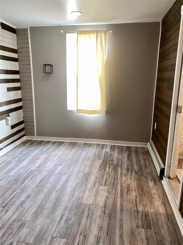 1008 4th Ave S, Great Falls, MT 59405 - unfurnished room featuring baseboard heating, wood finished floors, baseboards, and wooden walls