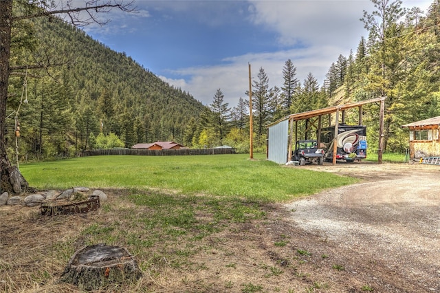 8229 York Rd, Helena, MT 59602 - view of grassy yard featuring a forest view, a carport, dirt driveway, and a mountain view