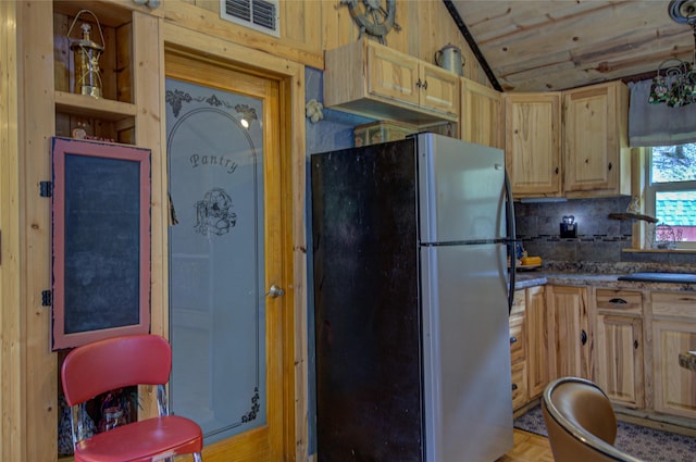 8229 York Rd, Helena, MT 59602 - kitchen featuring freestanding refrigerator, light brown cabinetry, lofted ceiling, a sink, and decorative backsplash