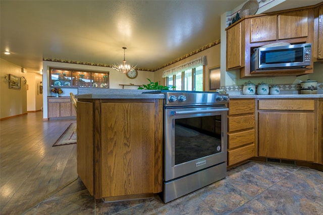 5380 US Highway 93, Conner, MT 59827 - kitchen featuring appliances with stainless steel finishes, a chandelier, brown cabinetry, a peninsula, and pendant lighting
