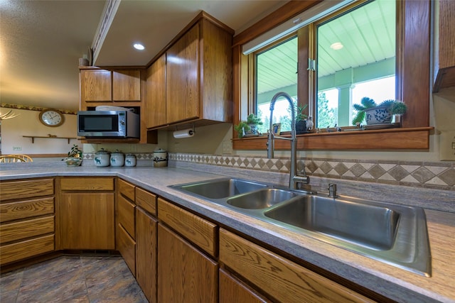 5380 US Highway 93, Conner, MT 59827 - kitchen with stainless steel microwave, a sink, brown cabinetry, dark stone finish floors, and light countertops