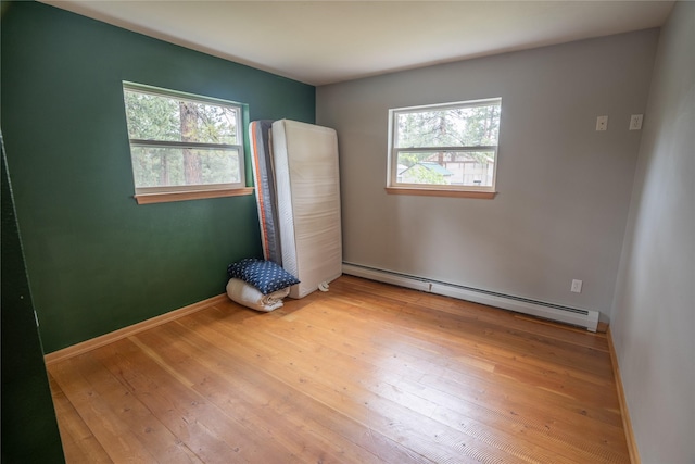 3185 Hubbart Dam Rd, Marion, MT 59925 - unfurnished bedroom with multiple windows, baseboard heating, and wood-type flooring