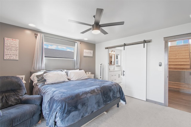 3870 Swan Rd, East Helena, MT 59635 - bedroom featuring a barn door, light carpet, ensuite bath, ceiling fan, and baseboards